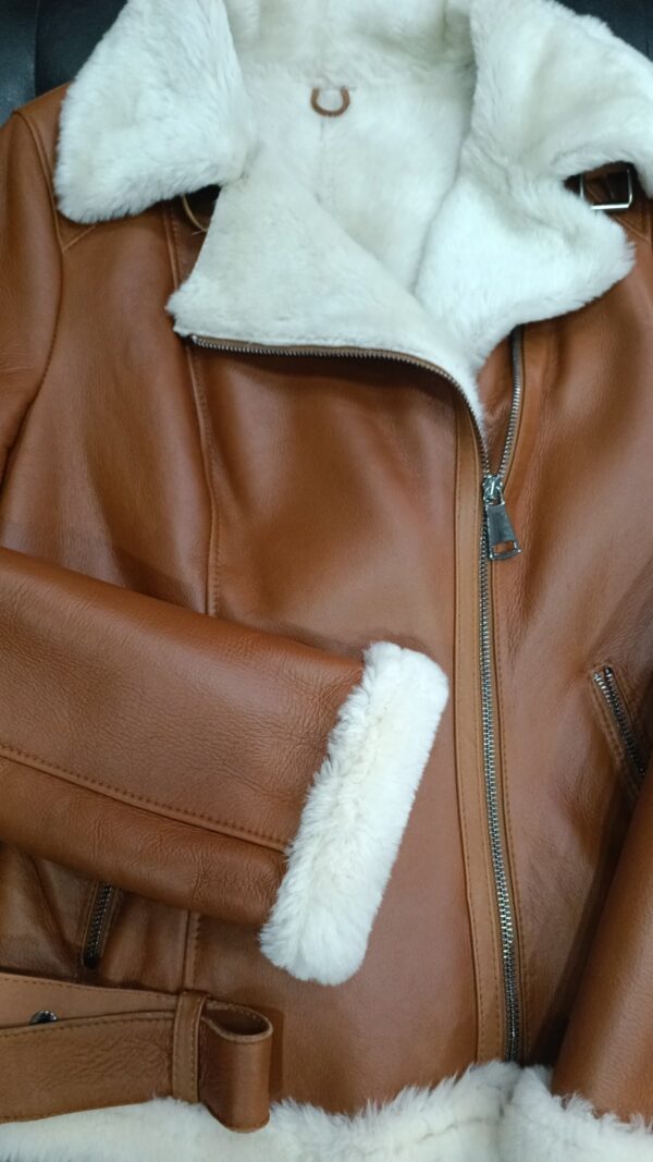 Дамски къс авиаторски кожух от ГОЯ Leather. Нов дамски кожух, изработен в класически за модела цвят на кожата камел със светъл косъм отвътре. Колекция ГОЯ Leather 2023г. Кожухът е изработен от агнешка тула с покритие и може да се носи и при влажно време.Разполага с типичните аксесоари за авиаторските модели, като метални ципове за закопчаване, колан в долната част и катарами на яката. . Има и два външни джоба . Лек и топъл дамски кожух за студените зимни дни.