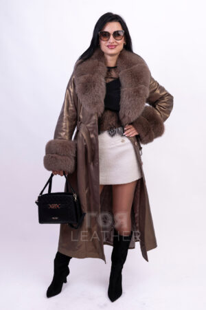 VK- R 56 | ЦВЯТ: Бронз Новият ни модел кожено манто VK- R 56 | ЦВЯТ: Бронз ще осигури на притежателката си несравнима привлекателност. Изработено от мека, висококачествена агнешка кожа, то вдъхва усещане за лукс и увереност във всяко движение. Меката текстура на материала осигурява перфектно прилягане, подчертавайки фигурата ви и позволявайки ви да се движите свободно. Особено впечатляваща характеристика е обемната, подвижна яка, изработена от естествена лисича кожа. Тя не само добавя изтънченост към визията, но и осигурява допълнителна защита от атмосферните условия в по-хладните дни. С едно лесно движение на китката яката може да се отдели, превръщайки палтото в по-семпъл вариант за по-топло време. Ръкавите също са допълнени с богати маншети от лисица,които са подвижни. За подчертаване на талията има колан с катарама. Дължината от 128 см. създава перфектен силует на фигурата. Уникалният цвят придава на това палто изисканост и класа.
