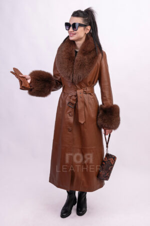 Новият ни модел кожено манто VK- R 56 | ЦВЯТ: Камел  ще осигури на притежателката си несравнима привлекателност. Изработено от мека, висококачествена агнешка кожа, то вдъхва усещане за лукс и увереност във всяко движение. Меката текстура на материала осигурява перфектно прилягане, подчертавайки фигурата ви и позволявайки ви да се движите свободно. Особено впечатляваща характеристика е обемната, подвижна яка, изработена от естествена лисича кожа. Тя не само добавя изтънченост към визията, но и осигурява допълнителна защита от атмосферните условия в по-хладните дни. С едно лесно движение на китката яката може да се отдели, превръщайки палтото в по-семпъл вариант за по-топло време. Ръкавите също са допълнени с богати маншети от лисица,които са подвижни. За подчертаване на талията има колан с катарама. Дължината  от 128 см. създава  перфектен силует на фигурата. Уникалният цвят придава на това палто изисканост и класа.